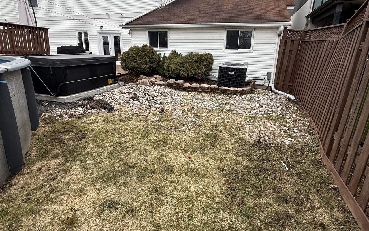 Tired backyard with dead grass and a rock bed before the Lauzon Home Services build