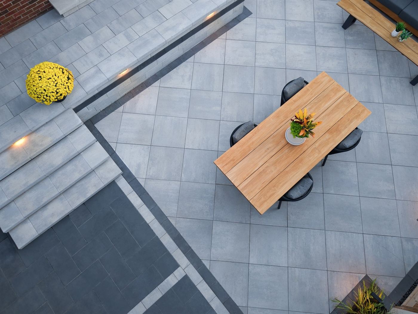 Aerial view of a grey interlock patio with dark banded borders, steps and a dining area