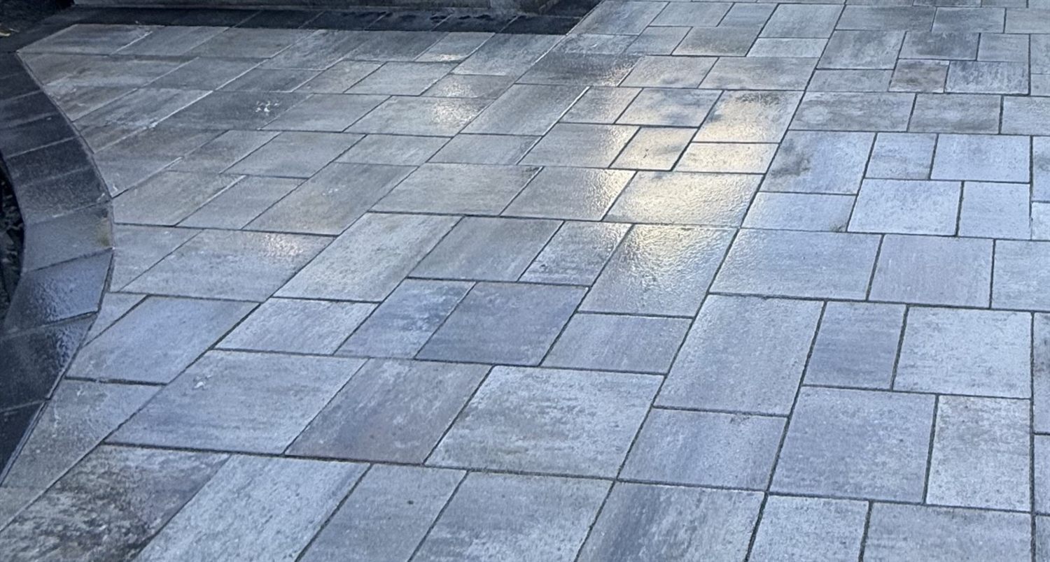 Close-up of large-format grey interlock pavers with a charcoal banded border