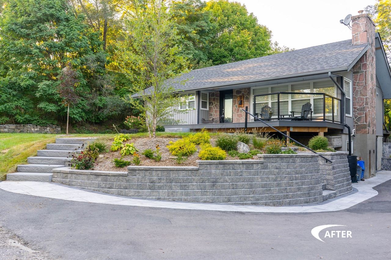 Tiered segmental retaining wall with steps and a planted terrace in front of a renovated home